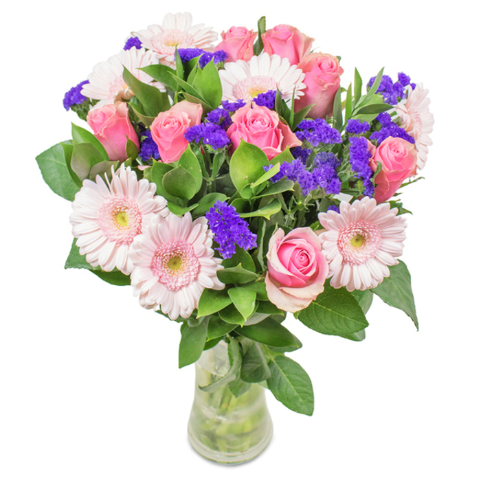 This elegantly composed bouquet, presented in a crystal-clear glass vase against a white background, is a quintessential creation from Cheam Flowers-crafted to encapsulate the local grace of Cheam. Approximately seven to nine pink roses form the heart of the arrangement, many with petals just opening to reveal their intricate spirals, symbolising new beginnings and timeless romance. Five to seven pale pink Gerbera daisies surround them, their wide faces and nearly white centers creating a luminous halo effect, reminiscent of the springtime displays along Park Road. Interspersed expertly are clusters of deep purple statice, their textured heads adding visual depth and a modern twist to the palette of pastels. Lush, variegated green foliage fills out the bouquet, evoking the abundant natural beauty found in and around Cheam's leafy streets. The bouquet is anchored in a transparent vase, the water clear and inviting, the stems precisely arranged for maximum freshness. Whether intended for Mother's Day, a special birthday on Ewell Road, or as a heartfelt addition to a welcoming home, this arrangement brings together the practical beauty and skilled artistry that Cheam Flowers is known for. Every element is chosen to evoke celebration, joy, and enduring affection.