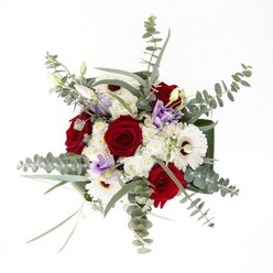 Crafted with an eye for elegant simplicity, this distinctive bouquet graces its surroundings like a familiar sight from a Cheam garden, blending modern composition with classic floral grace. The white gerberas, bold yet understated, set a serene foundation, their petals arranging themselves meticulously around dark chocolate-brown centers. Nestled close, velvety red roses rise in spiralled tiers, each inviting a tactile appreciation of their lush, layered nature. Above and between, sprigs of eucalyptus fan out in arcs-silvery and cool-delivering both visual and aromatic freshness that recalls walks along Sandy Lane on a brisk day. Gentle sprays of pale lavender lisianthus, both open and in bud, introduce a nuanced palette, their presence akin to tender new blooms at dawn. Soft, clustered white filler flowers bring volume and a dew-like softness, ensuring the bouquet retains a breezy, inviting spirit. Encasing it all, broad, glossy green leaves wrap at the base, creating a harmonious frame, while the crystal vase reveals stems standing in fresh, clear water-a subtle pledge of the arrangement's vitality. Designed with the discerning residents of Cheam in mind, this bouquet is tailor-made for celebrations, tokens of appreciation, or simply infusing a room with the genuine beauty crafted by local floral artisans.