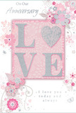 This anniversary card feels like a gentle whisper of devotion, designed in the soft pastel tones and silvery accents that echo the calm character of Cheam's tree-lined avenues. At its heart stands the word LOVE, each letter raised from the surface and coated in a soft, fine glitter that adds both texture and a subtle, shimmering glow. The O becomes a shining silver heart, slightly more textured and luminous than the surrounding letters, drawing the eye as the emotional centre of the design. Around this central motif, delicate flowers in blush, mauve, and pale ivory unfold in a style that suggests watercolour painting, their edges gently blurred and their stems and tendrils rendered in flowing lines. Small flourishes-tiny petals, swirling scrolls, and discreet butterflies-play among the blossoms, adding movement and a hint of whimsy, much like watching petals move in a light breeze over Cheam Common. Slender touches of silver highlight parts of the flowers and curls, catching ambient light with a refined sparkle that recalls satin ribbon on a carefully wrapped bouquet. The inscriptions On Our Anniversary and I love you today and always appear in an elegant, flowing script, positioned to frame the central artwork without overshadowing it. The background is bathed in gentle, even light, enhancing the calm pastel tones and ensuring the raised glitter and metallic threads remain noticeable but never harsh. The overall mood is intimate and heartfelt-a keepsake that would sit beautifully beside a vase of fresh anniversary flowers delivered to a home in Cheam, quietly honouring a shared journey of love.